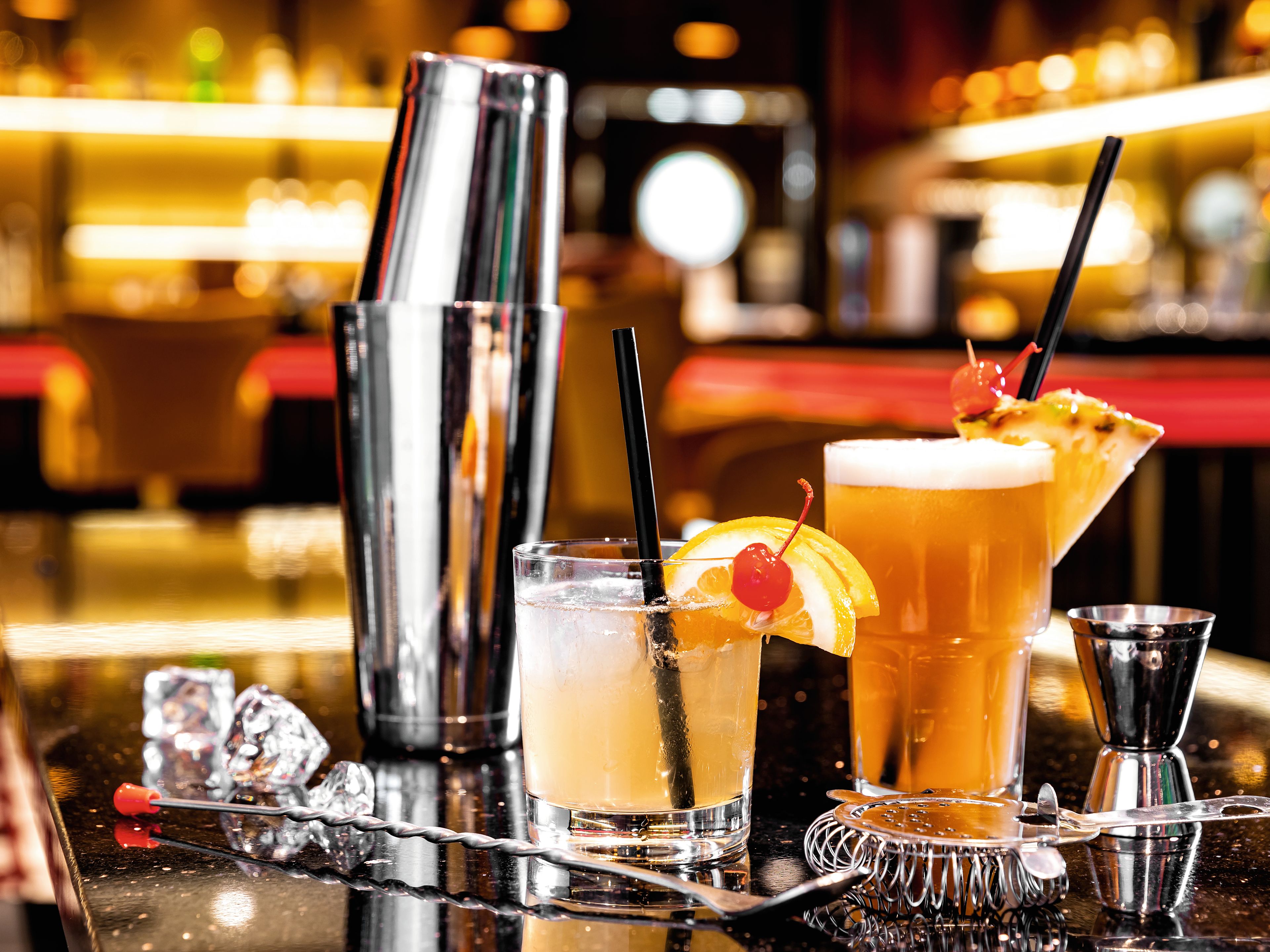 Cocktails mit Früchten und Shaker auf glänzendem Tresen. Cocktails mit Früchten und Shaker auf glänzendem Tresen.