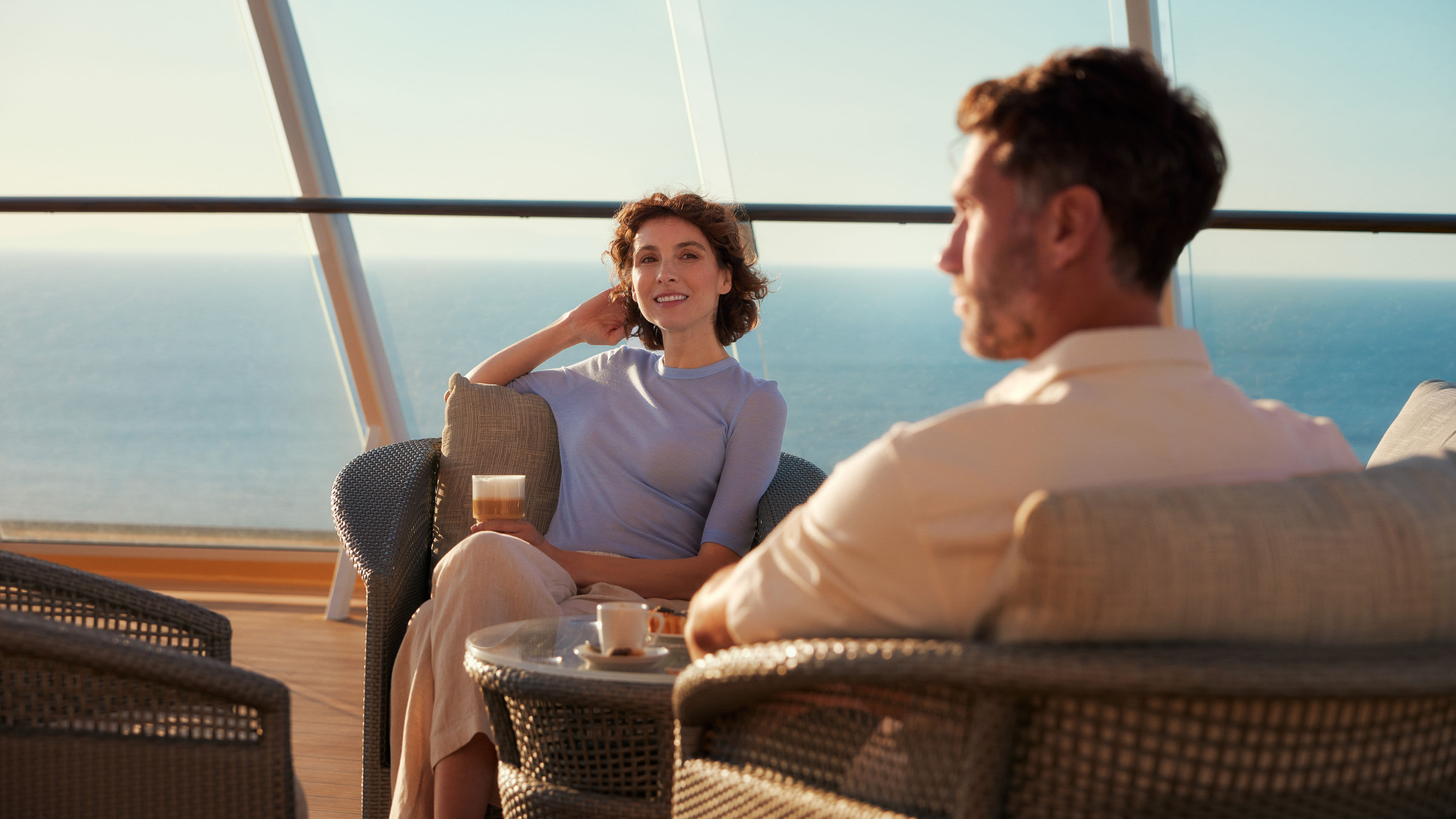 Paar genießt Kaffee auf Kreuzfahrtschiff der Mein Schiff® Flotte mit Meerblick.