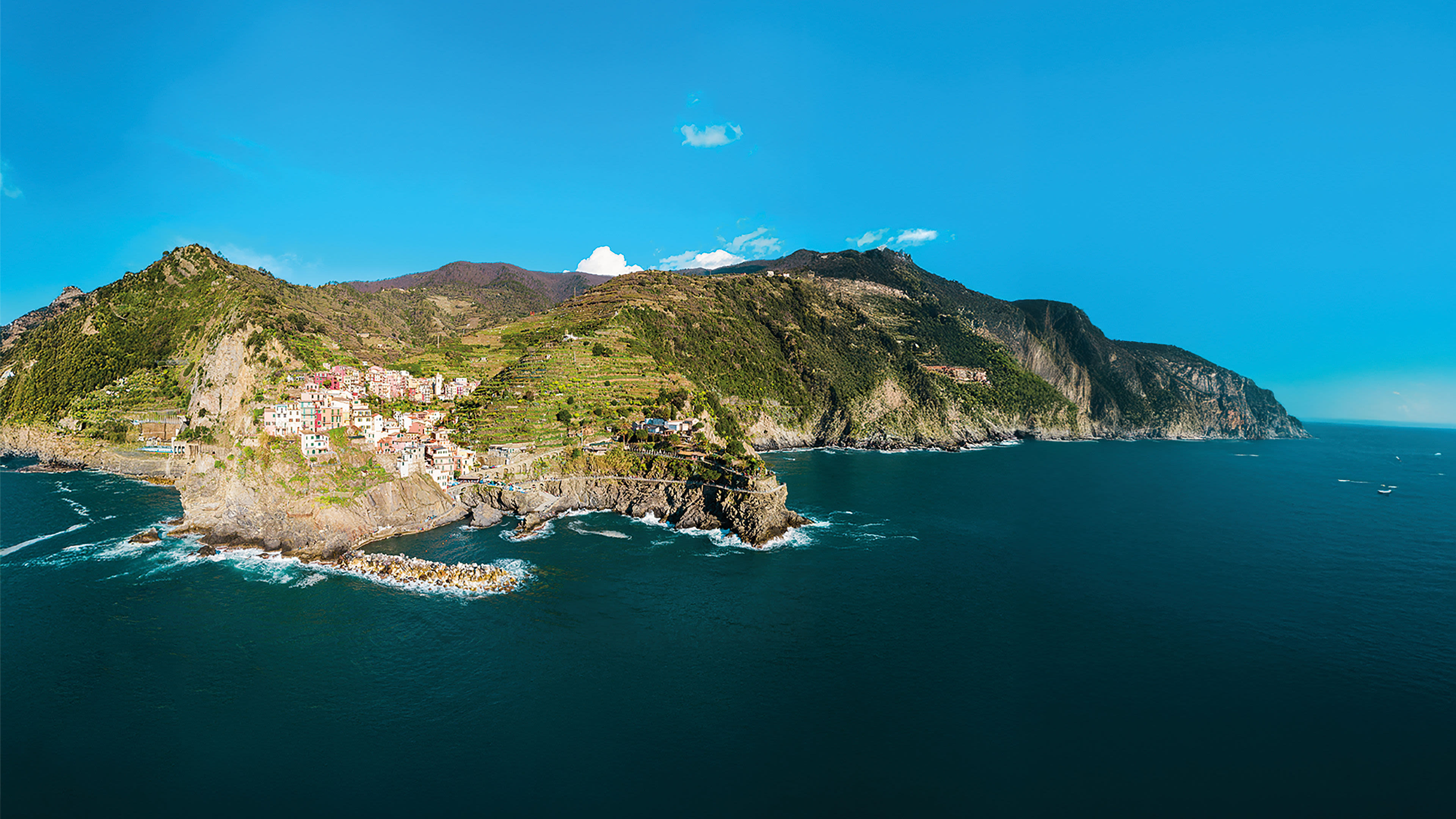 Küstenstadt Cinque Terre, bunte Häuser, blaues Meer, grüner Hügel.