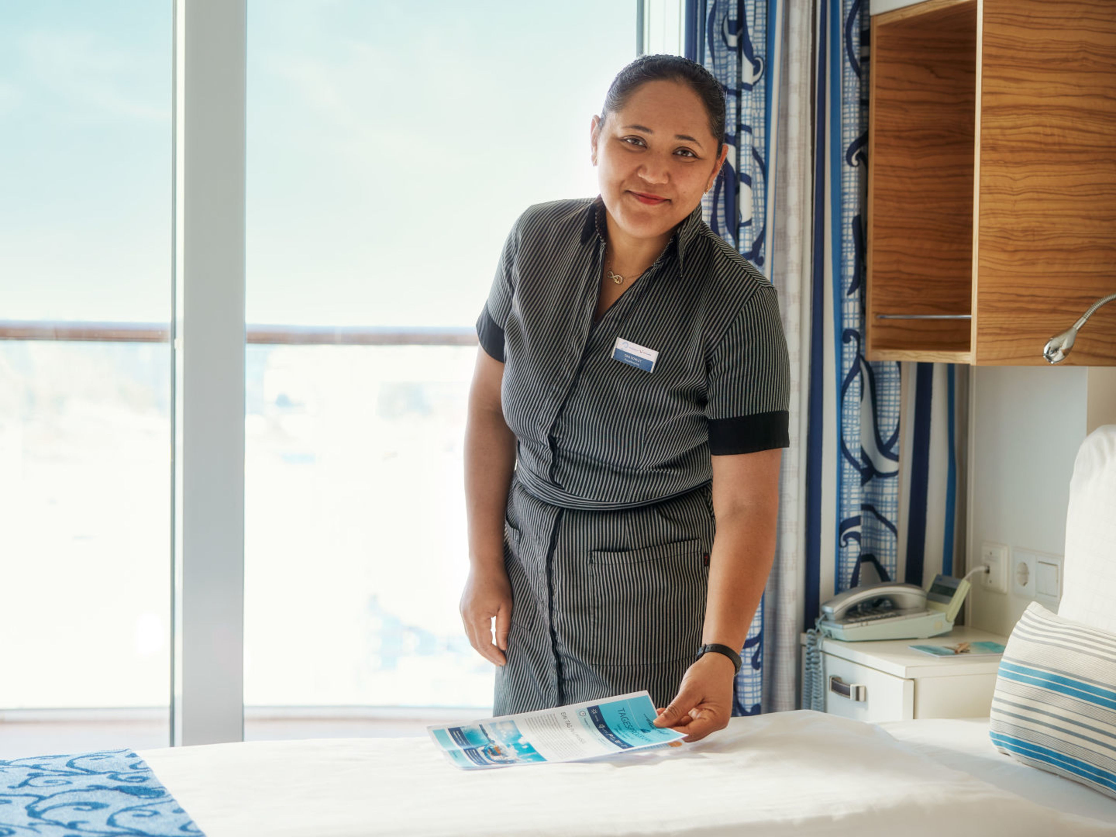 Frau richtet Bett in Kreuzfahrtschiffkabine der Mein Schiff® Flotte. Frau richtet Bett in Kreuzfahrtschiffkabine der Mein Schiff® Flotte.