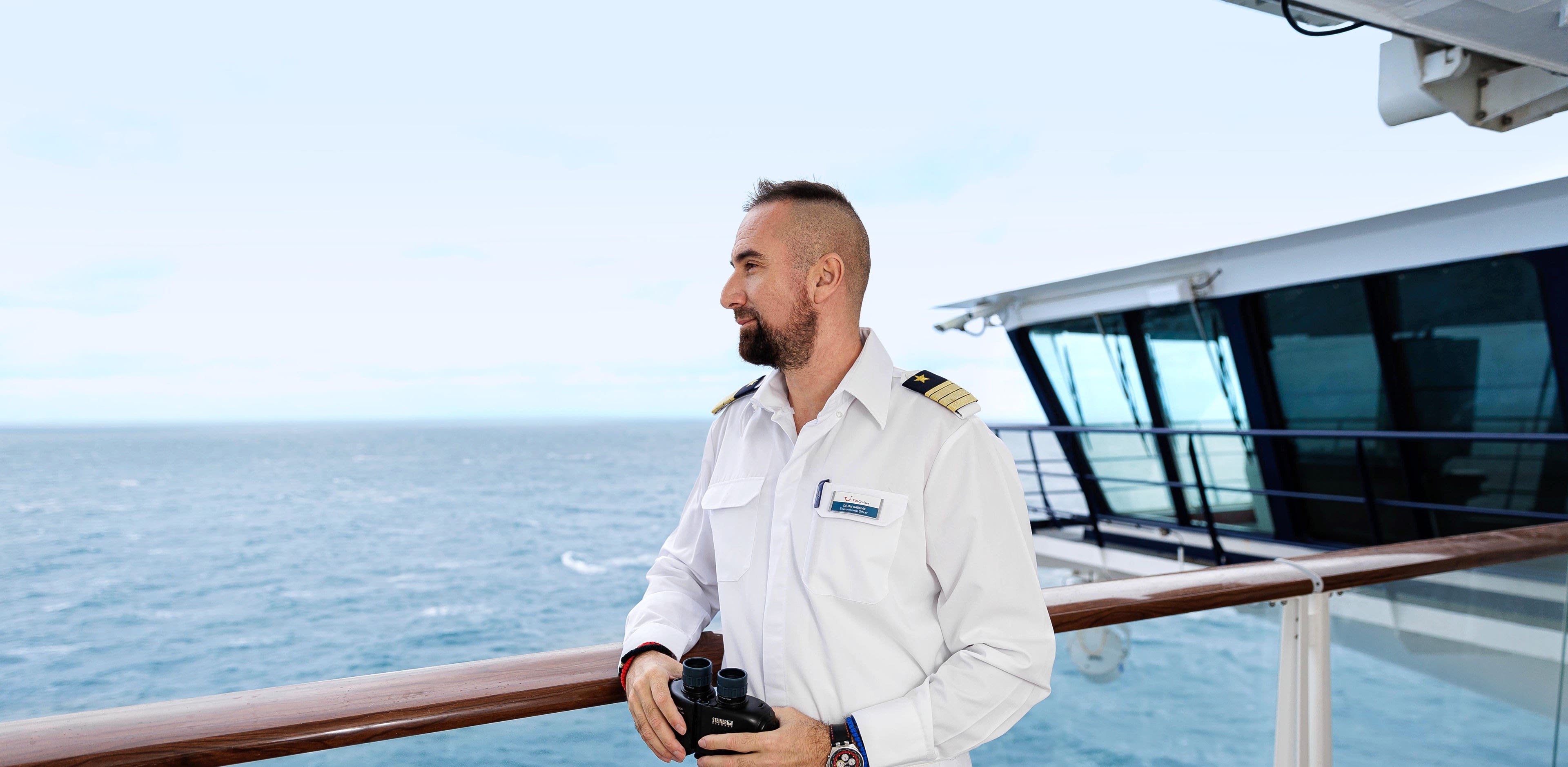 Mann in Uniform mit Fernglas auf Kreuzfahrtschiff der Mein Schiff® Flotte. Mann in Uniform mit Fernglas auf Kreuzfahrtschiff der Mein Schiff® Flotte.