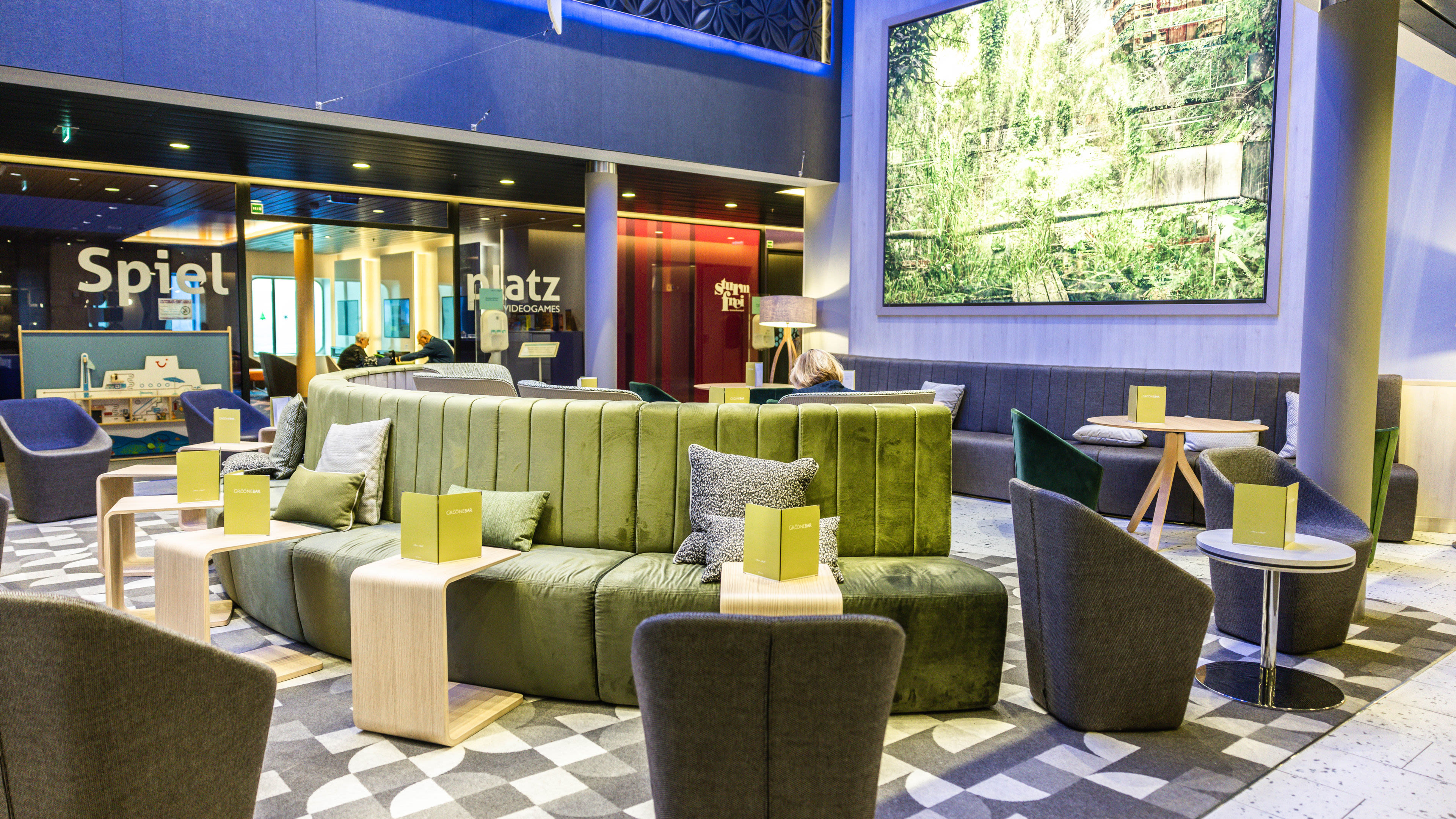 Moderne Lounge mit grünen Sofas, Tischen und Wandkunst.
