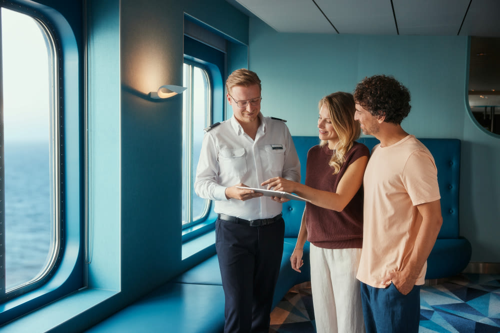 Drei Personen auf Kreuzfahrtschiff, Meerblick durch Fenster.