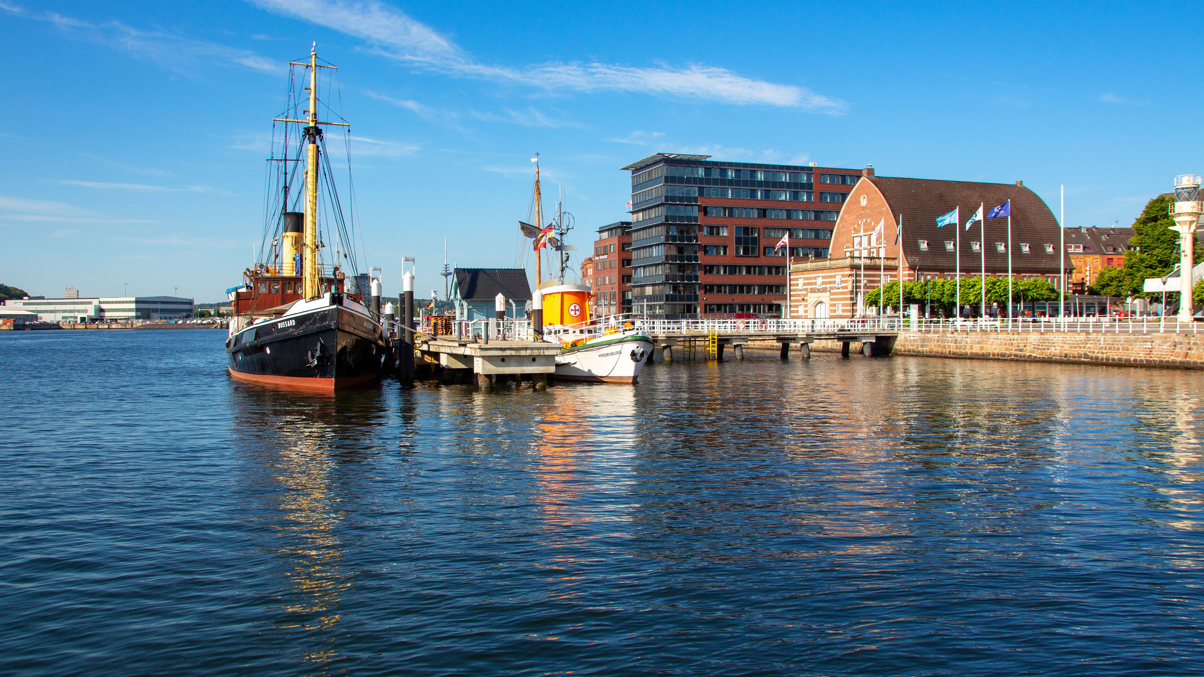 Hafen von Kiel mit historischen Schiffen und Gebäuden bei blauem Himmel. Hafen von Kiel mit historischen Schiffen und Gebäuden bei blauem Himmel.