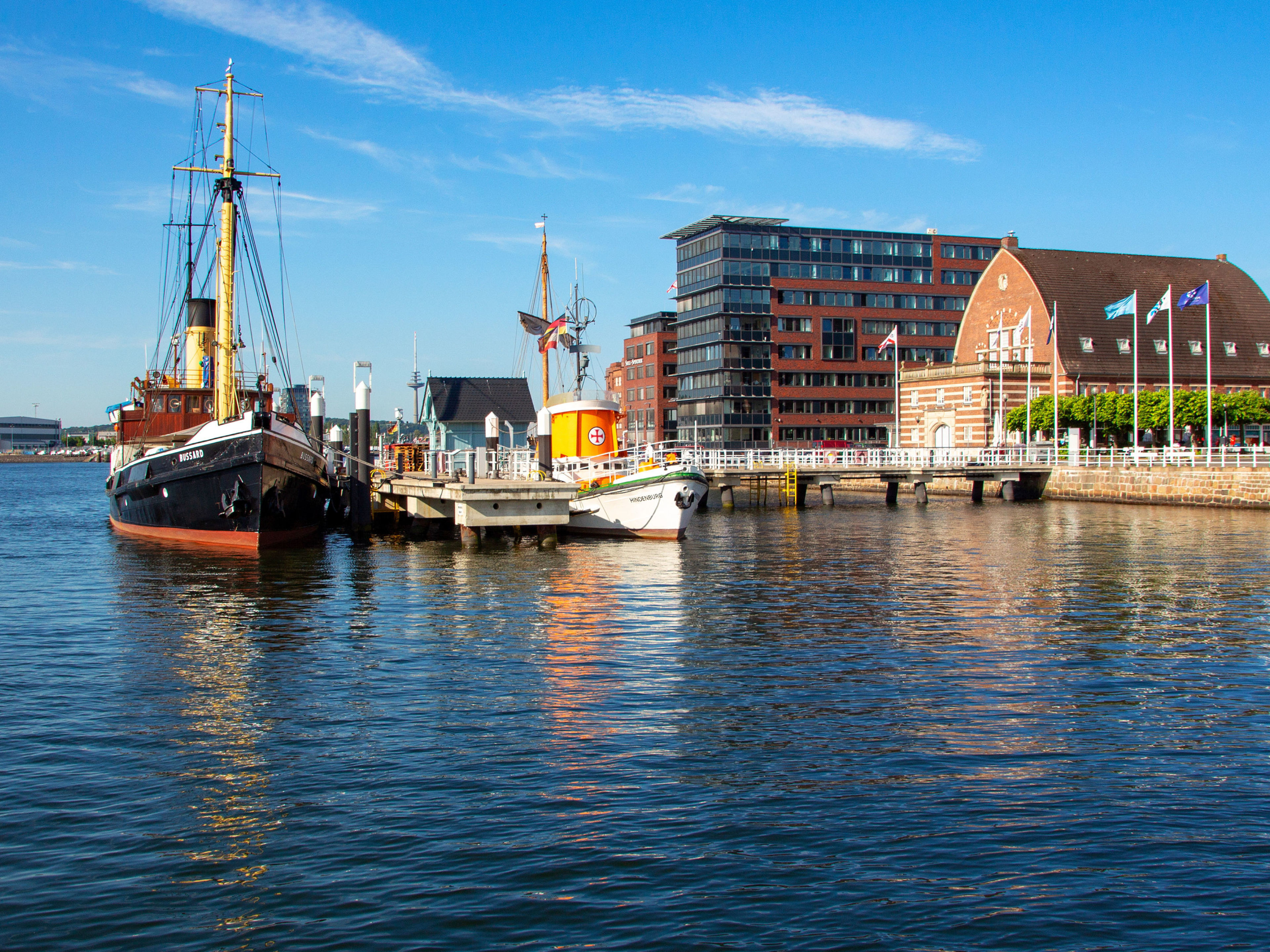 Hafen von Kiel mit historischen Schiffen und Gebäuden bei blauem Himmel. Hafen von Kiel mit historischen Schiffen und Gebäuden bei blauem Himmel.