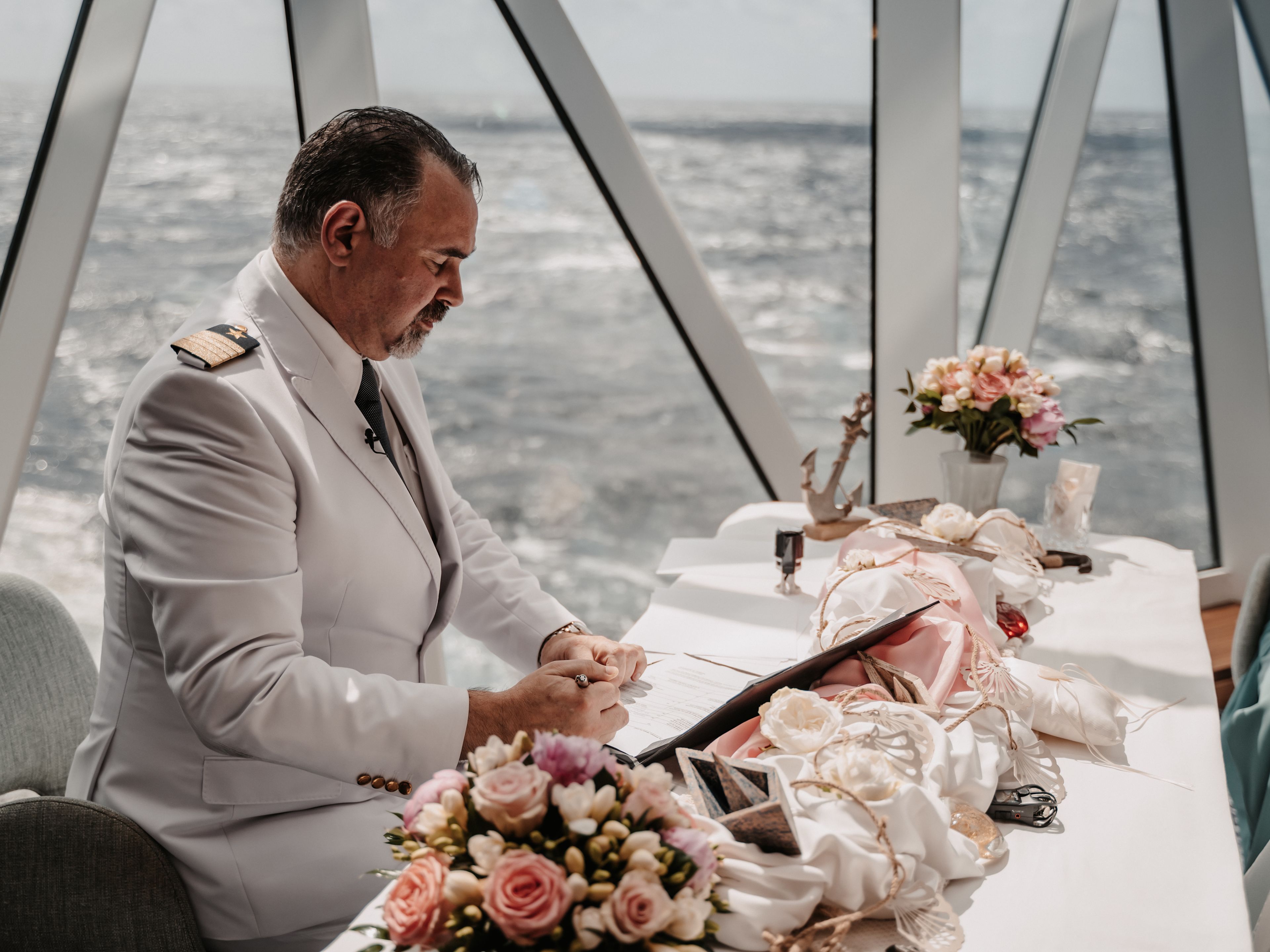 Kapitän in weißer Uniform bei Hochzeit auf Kreuzfahrtschiff, Blumenarrangement. Kapitän in weißer Uniform bei Hochzeit auf Kreuzfahrtschiff, Blumenarrangement.