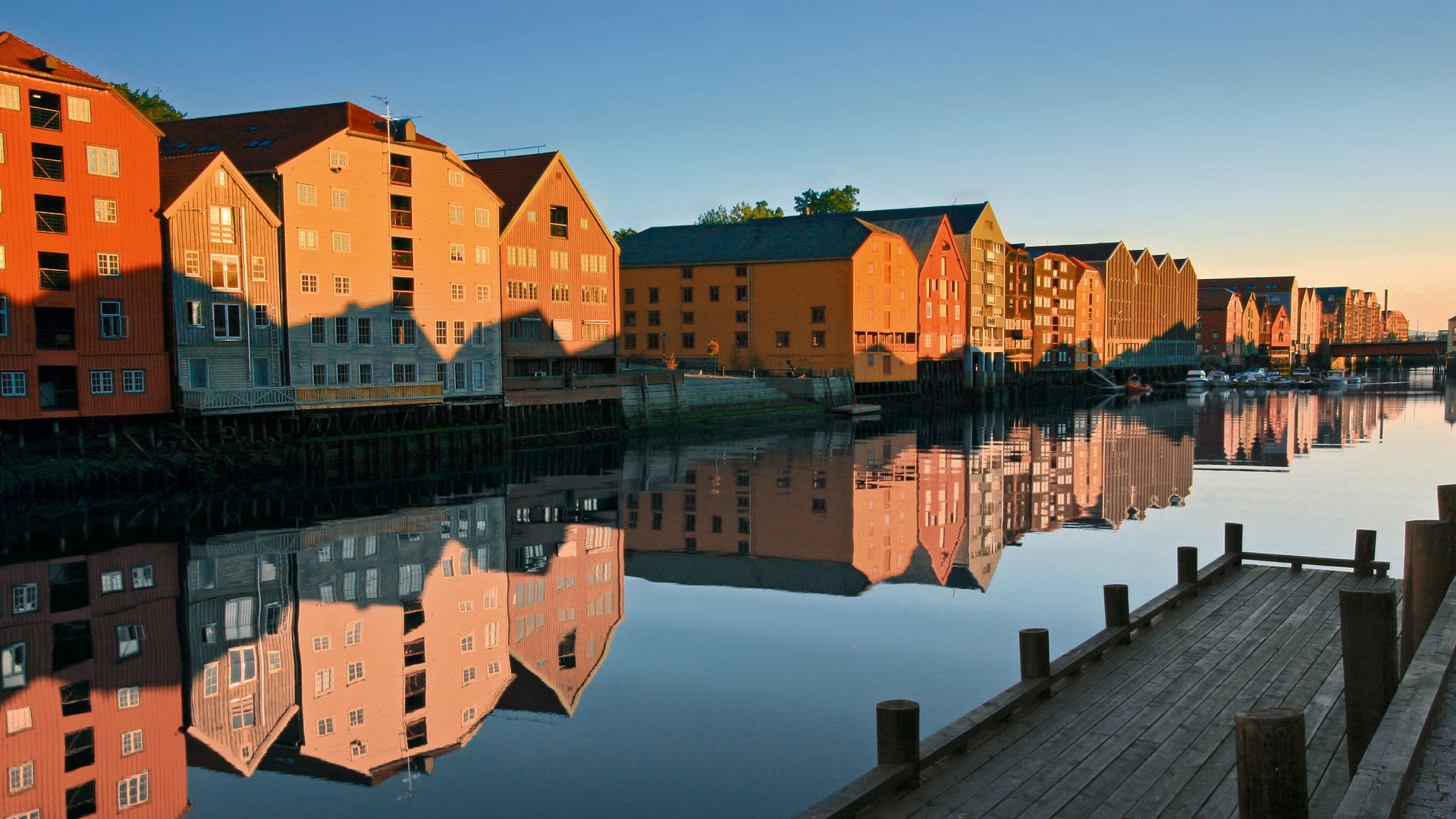 Bunte Lagerhäuser spiegeln sich im Fluss in Trondheim.