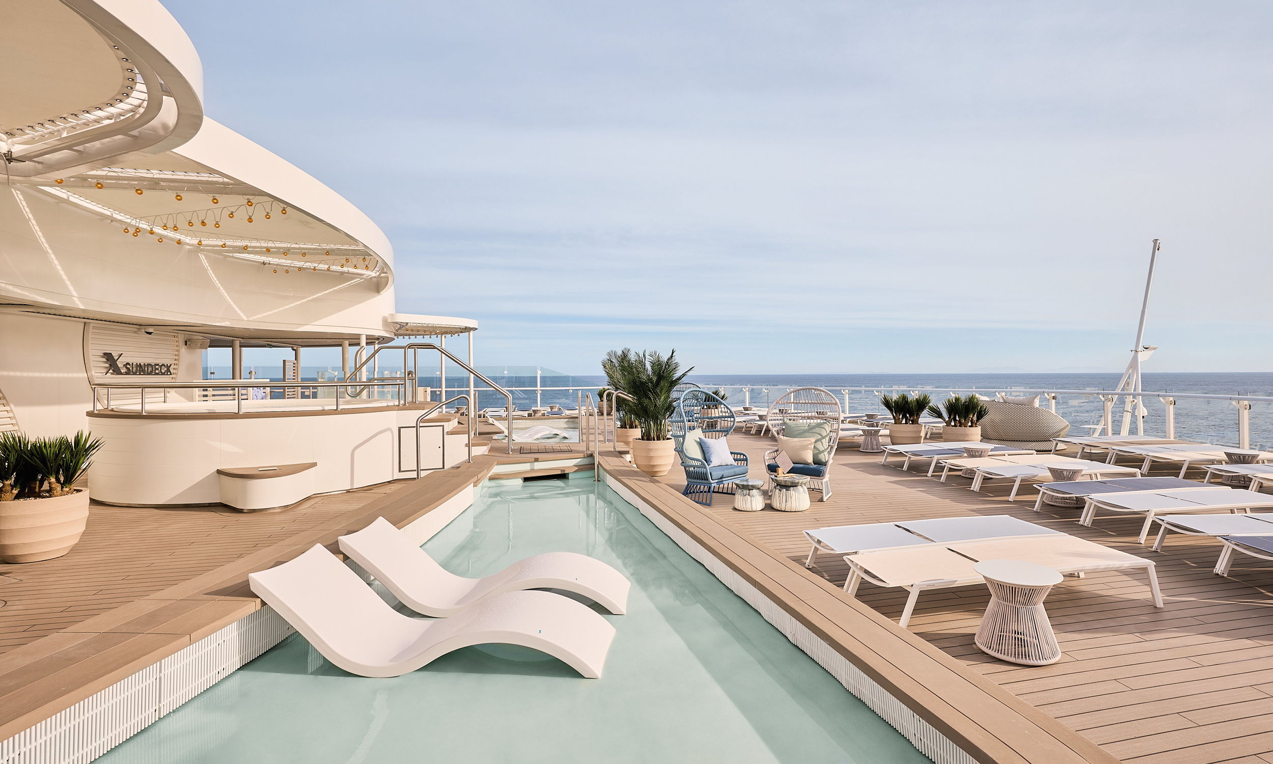 Sonnendeck mit Pool und Liegestühlen auf Kreuzfahrtschiff der Mein Schiff® Flotte.