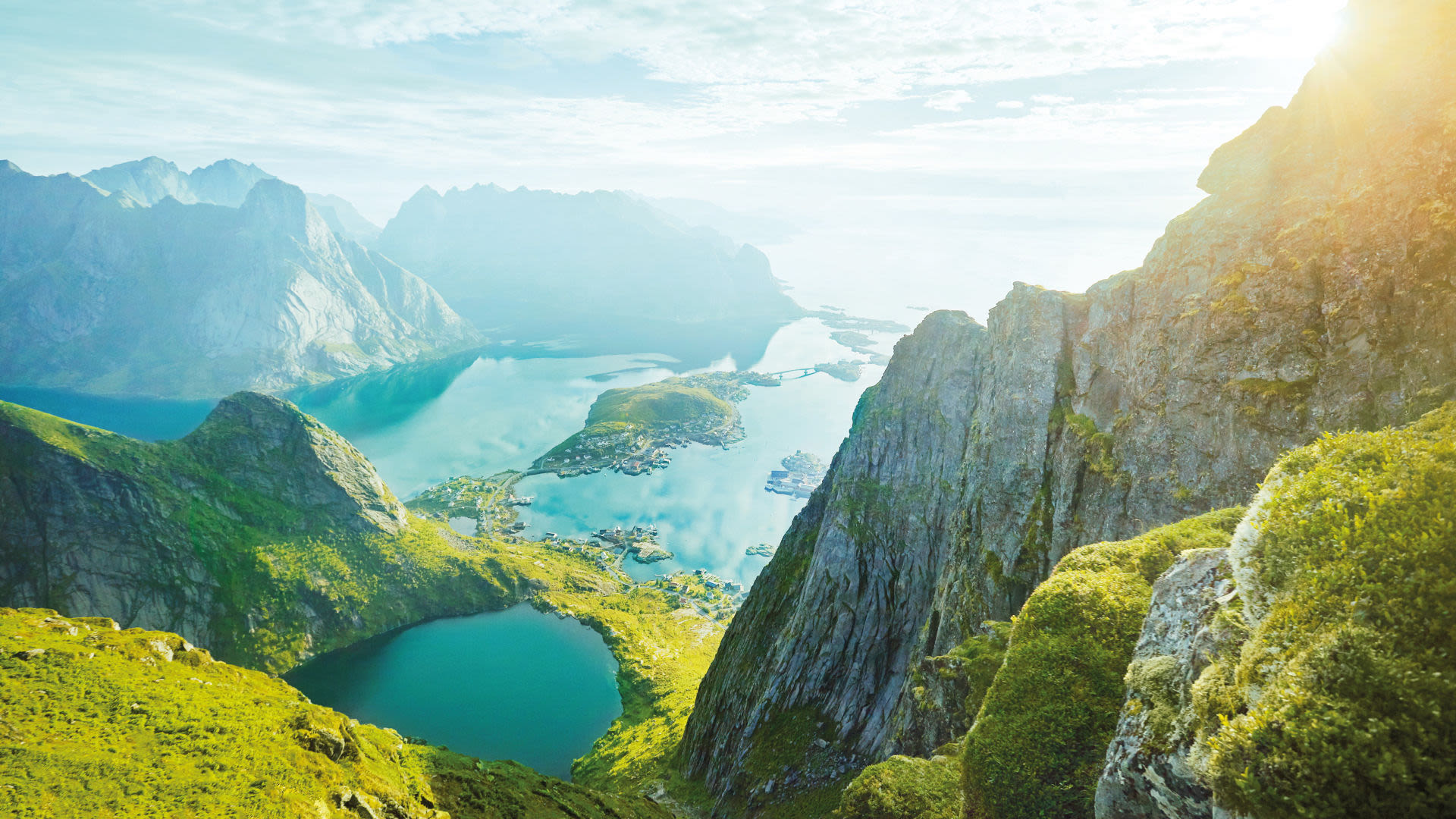 Blick auf die Lofoten, Norwegen, mit Bergen und Fjorden im Sonnenlicht.