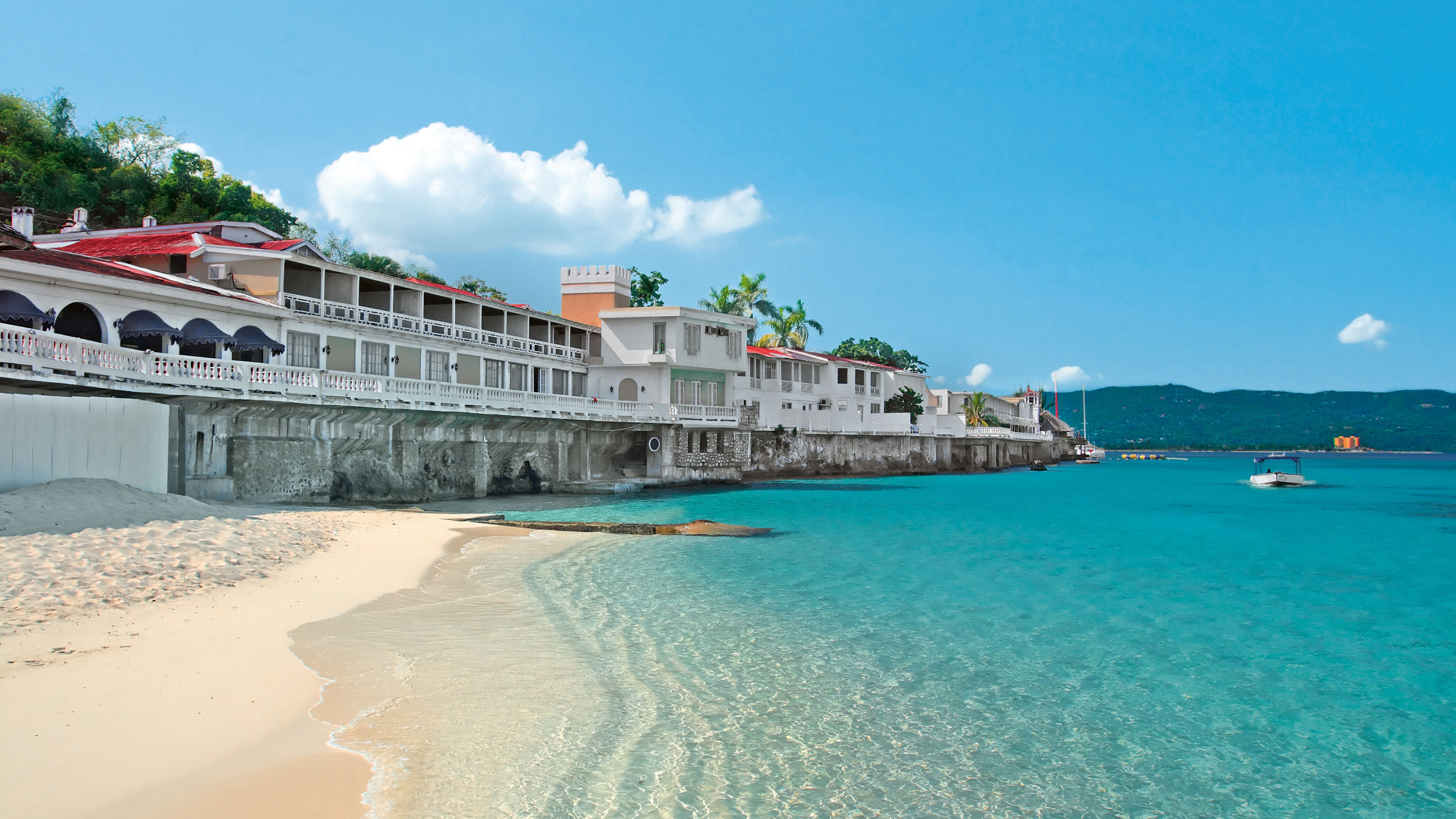 Strand mit türkisfarbenem Wasser, weißen Gebäuden und Booten. Strand mit türkisfarbenem Wasser, weißen Gebäuden und Booten.