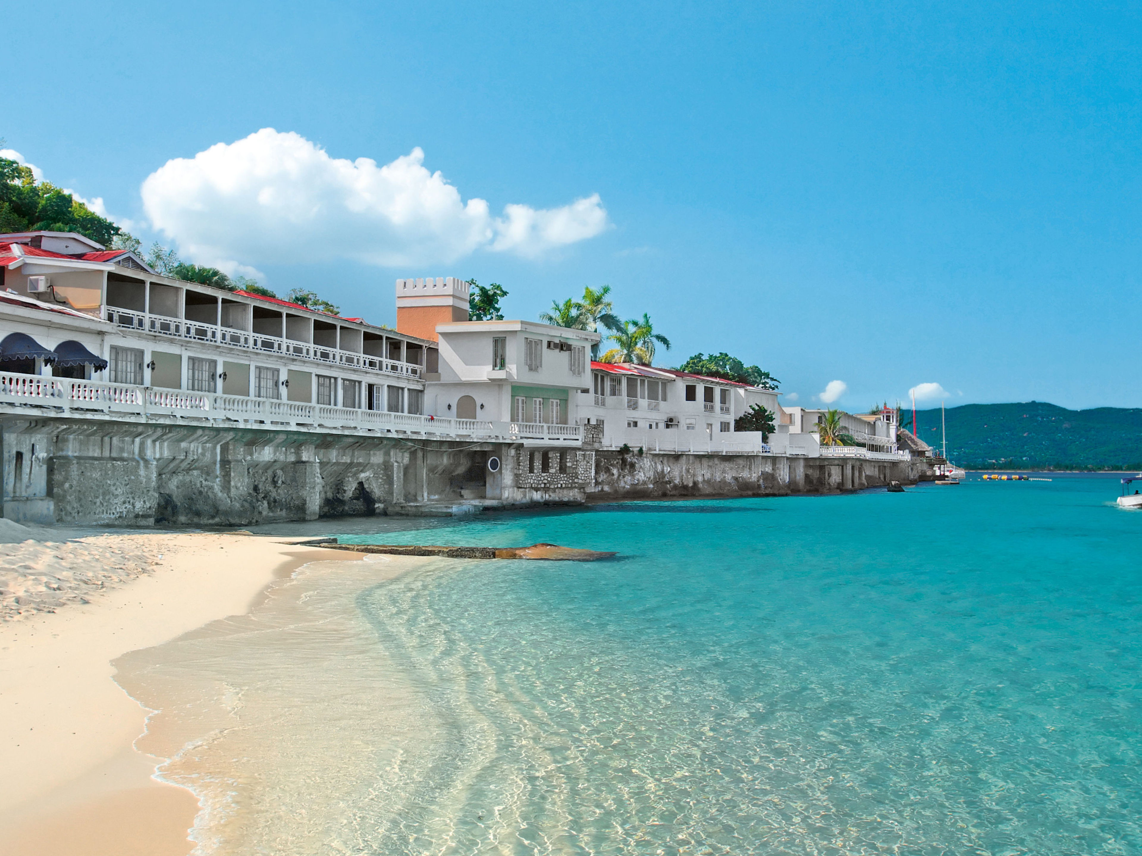 Strand mit türkisfarbenem Wasser, weißen Gebäuden und Booten. Strand mit türkisfarbenem Wasser, weißen Gebäuden und Booten.