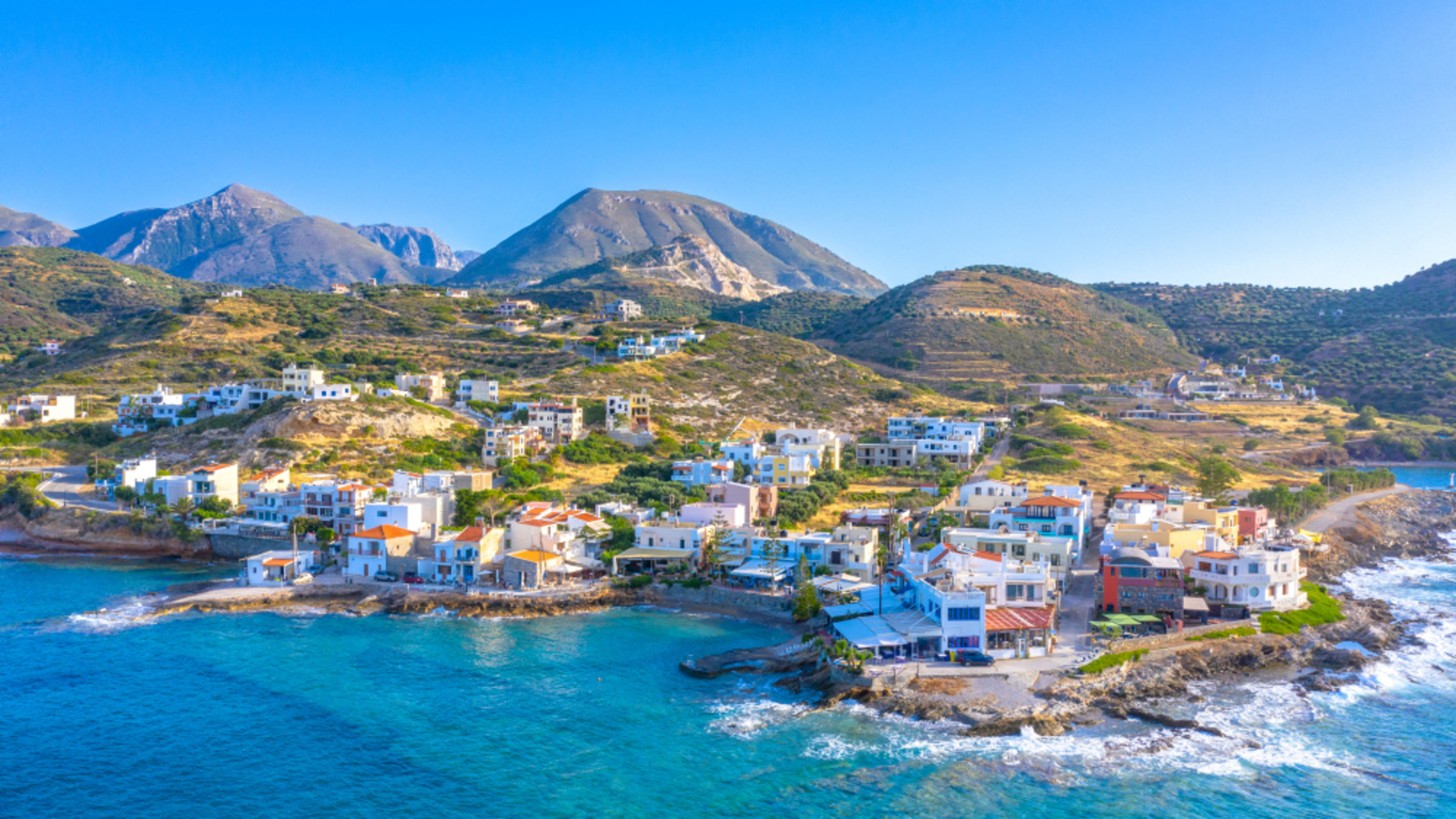 Küstenstadt auf Kreta mit bunten Häusern und Bergen im Hintergrund. Küstenstadt auf Kreta mit bunten Häusern und Bergen im Hintergrund.