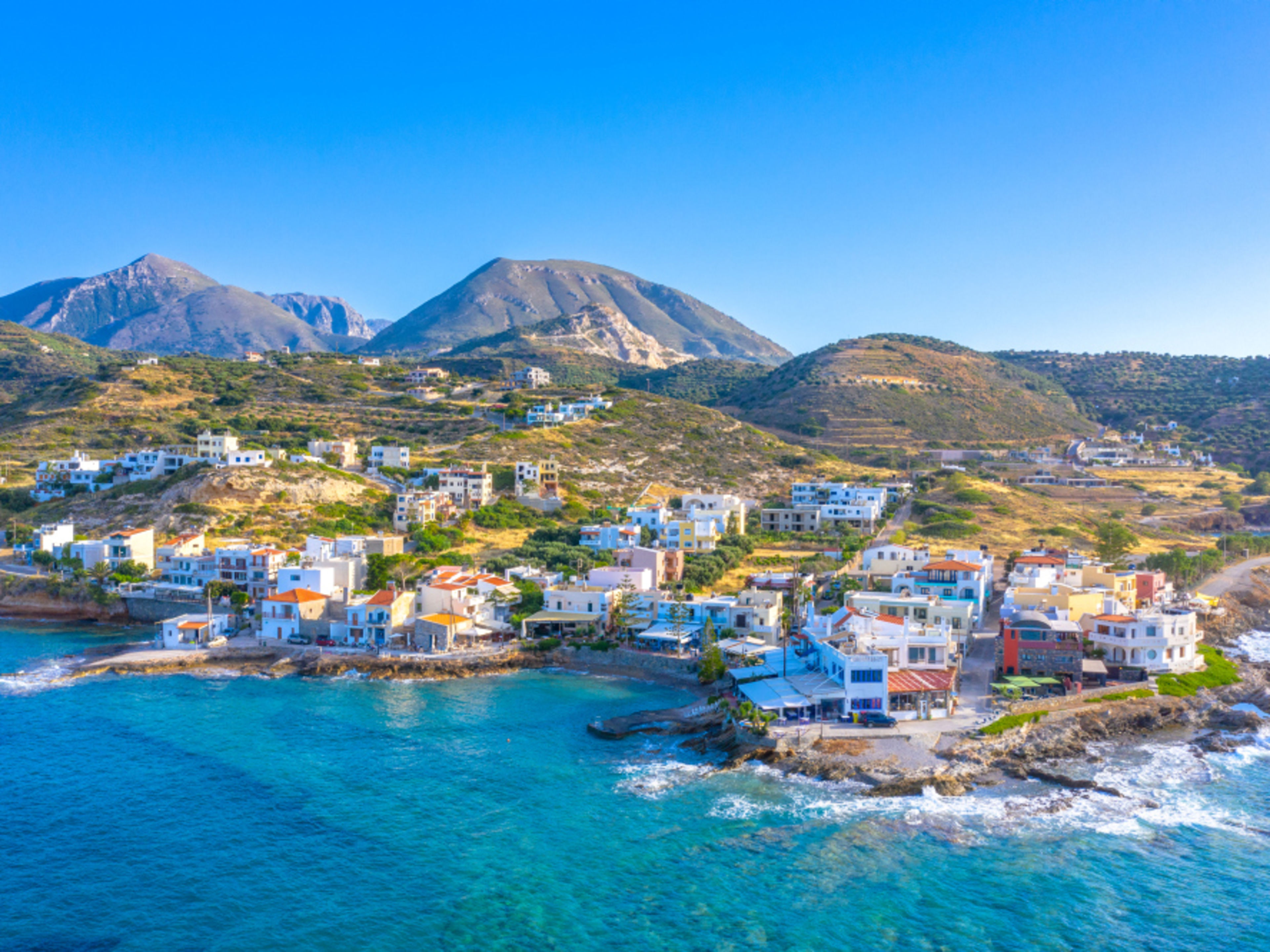 Küstenstadt auf Kreta mit bunten Häusern und Bergen im Hintergrund. Küstenstadt auf Kreta mit bunten Häusern und Bergen im Hintergrund.