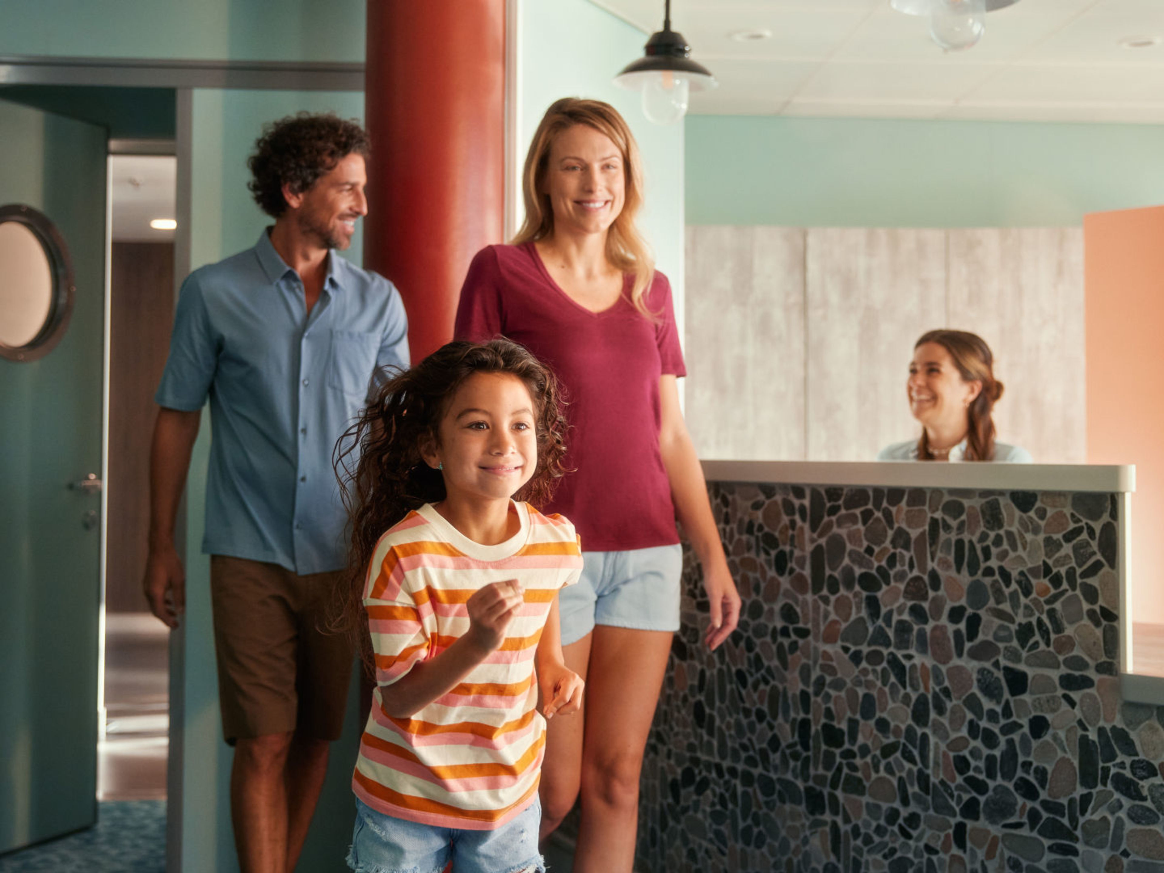 Familie betritt lächelnd Hotelrezeption, Empfangsdame begrüßt sie. Familie betritt lächelnd Hotelrezeption, Empfangsdame begrüßt sie.