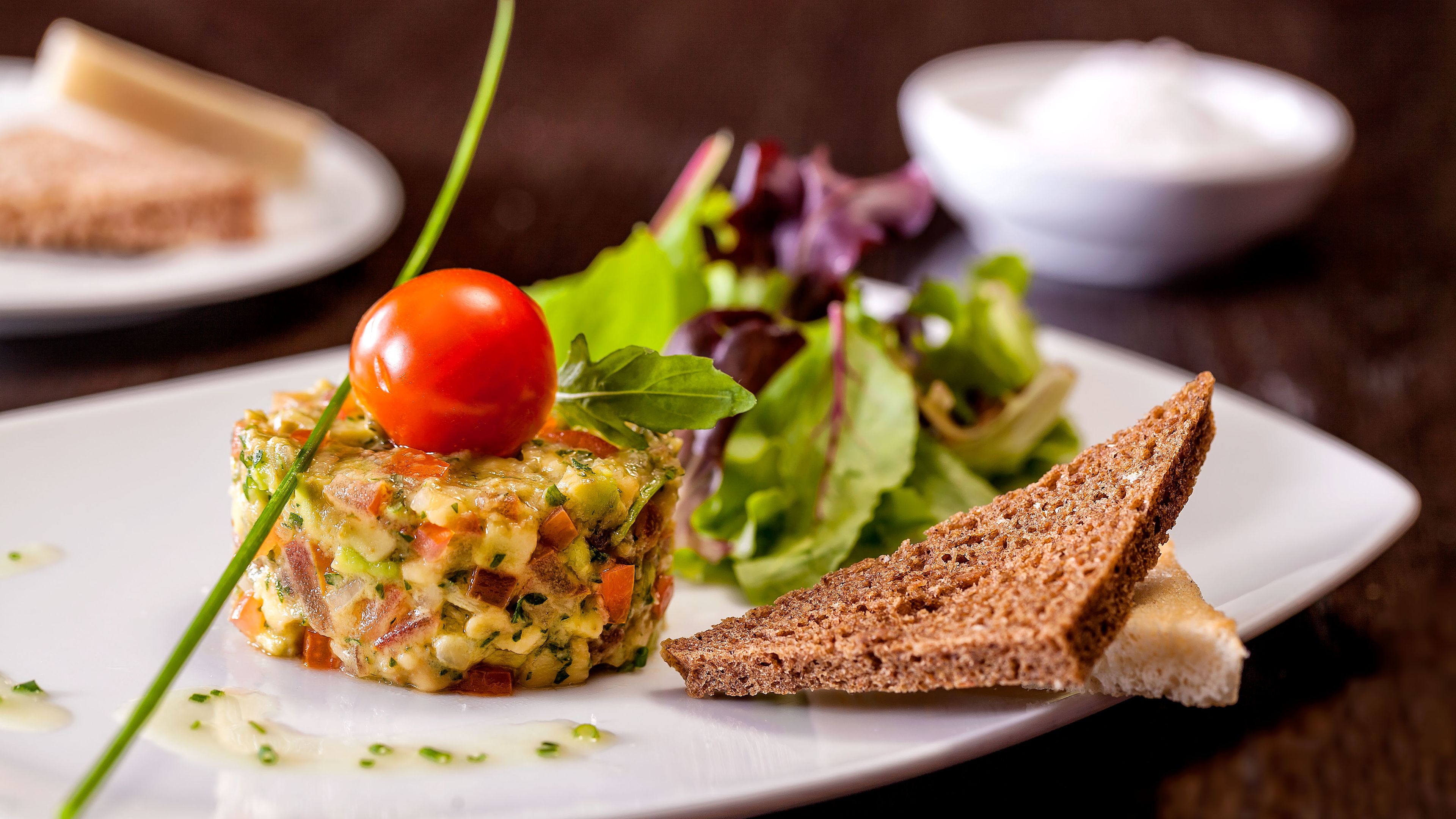 Gourmet-Vorspeise mit Tomate, Salat und Brot auf weißem Teller. Gourmet-Vorspeise mit Tomate, Salat und Brot auf weißem Teller.