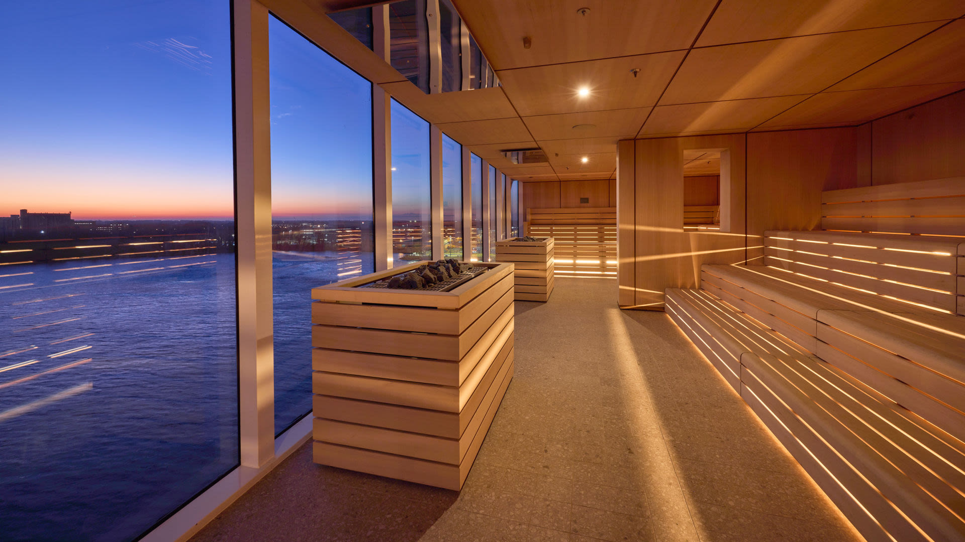 Sauna mit Panoramafenster, Blick auf Fluss bei Sonnenuntergang.