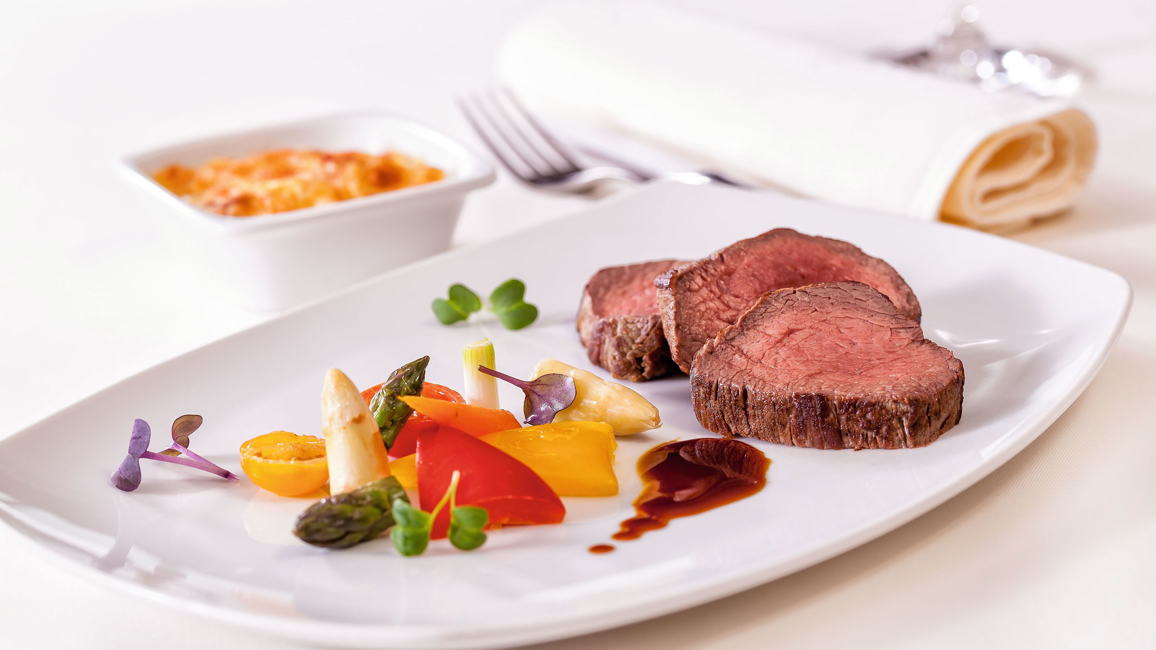 Rinderfilet mit Gemüse und Soße auf weißem Teller, elegant serviert. Rinderfilet mit Gemüse und Soße auf weißem Teller, elegant serviert.